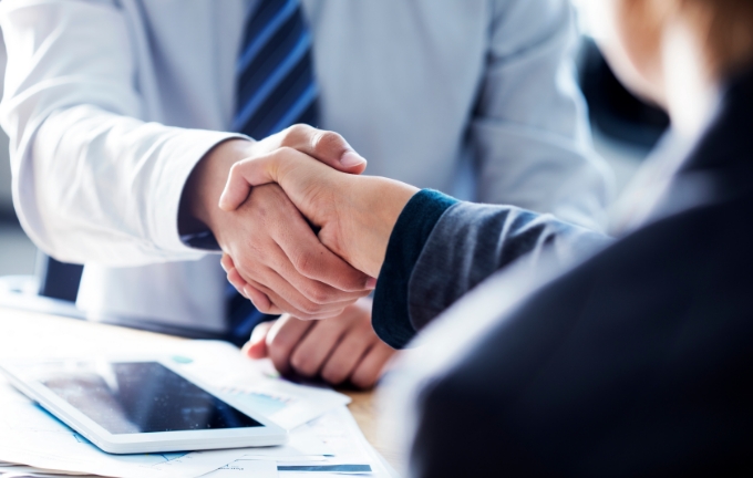 ビジネスパーソン同士が握手を交わしている場面。営業支援やコンサルティングの成果を示すイメージ。