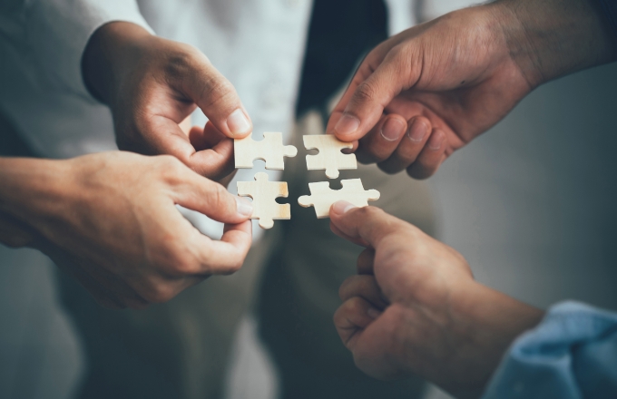 複数の手がパズルのピースを組み合わせている様子。人材のマッチングやチーム形成を象徴するイメージ。